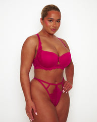 Angled view of Tutti Rouge Daley Lace bra in Cherry on a model, showing underwired cups and lace side panels, worn with a strappy thong.