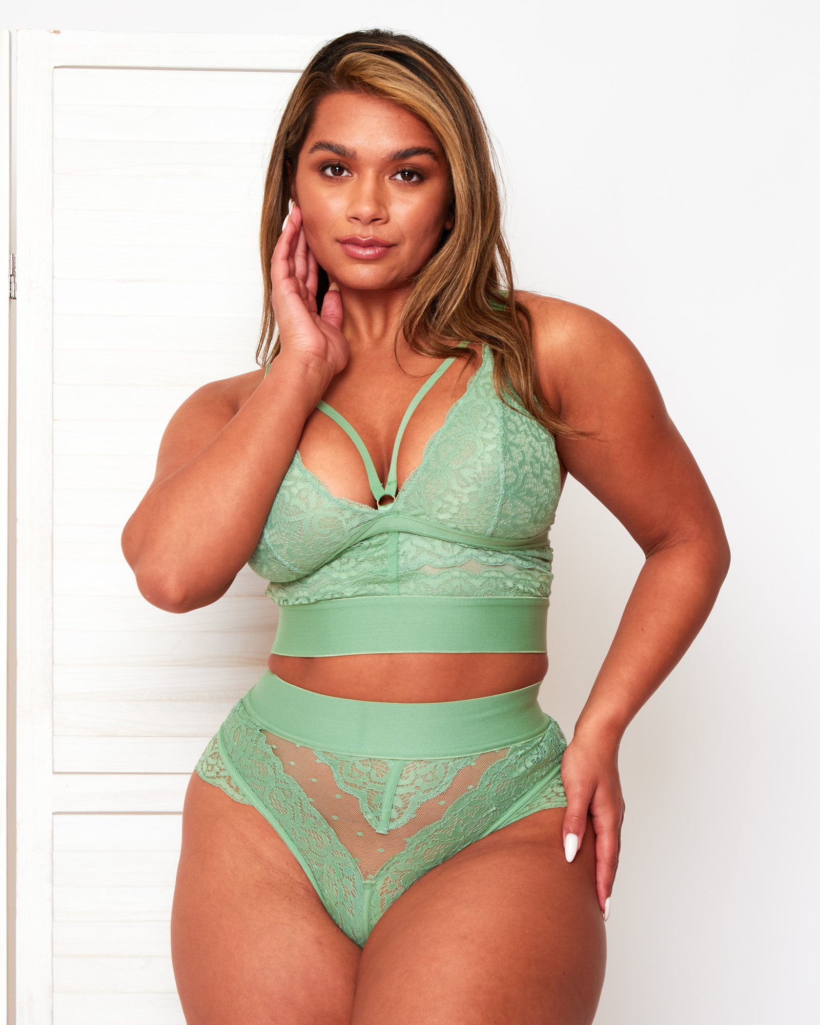 Model wearing the Tutti Rouge Gia Basil Green lace bralette with neckline straps and a matching high-waisted lace thong.