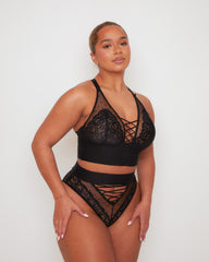 Side profile of the Tutti Rouge Maya Bralette in Midnight Black paired with the matching Maya High Waist Brief, showcasing delicate floral lace, sheer dotted mesh and bold lace-up details.