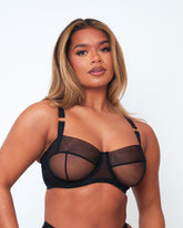 Close-up of Tutti Rouge Raya black balcony bra on a model, showing sheer mesh cups, black seam detailing and gold strap rings.