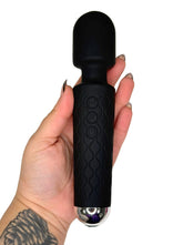 Black handheld massager held in a hand on a white background