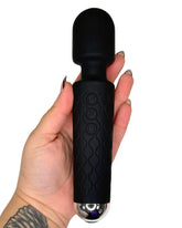 Black handheld massager held in a hand on a white background