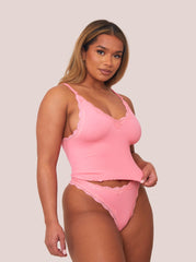 Woman wearing a pink lingerie set against a plain background