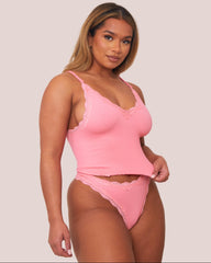 Woman wearing a pink lingerie set against a plain background