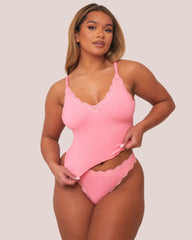 Woman wearing a pink lingerie set against a plain background