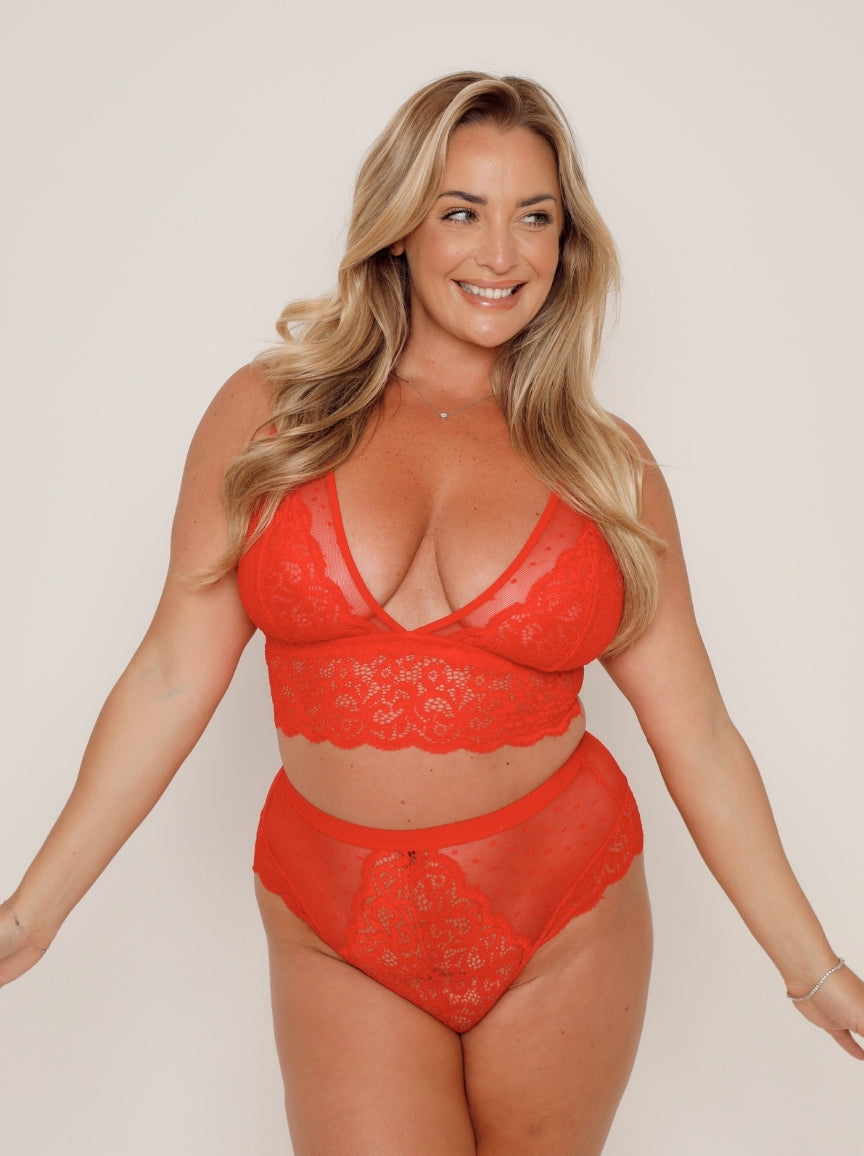 Woman wearing a red lace lingerie set on a plain background