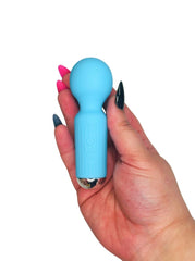 Hand holding a blue personal massager adult toy against a white background