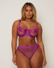 Woman wearing a purple lingerie set against a plain background