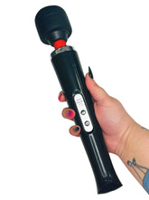 Hand holding a black personal massager wand with a white background