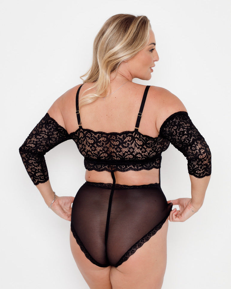Curve model wearing the Tutti Rouge Alix Bodysuit in Midnight Black, showcasing supportive fit and flattering sheer mesh back design.