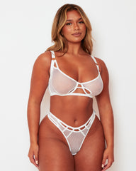 Model wearing the Tutti Rouge Aphrodite white fishnet lingerie set with gold-tone strap rings and a cut-out waistband.