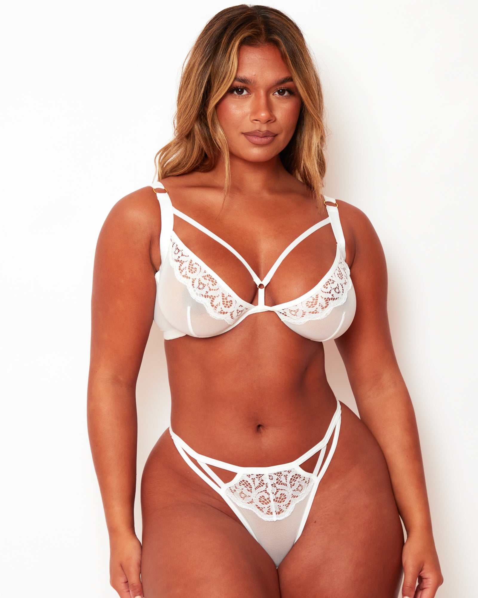Model wearing Tutti Rouge Artemis white lace and mesh plunge bra with matching strappy thong.