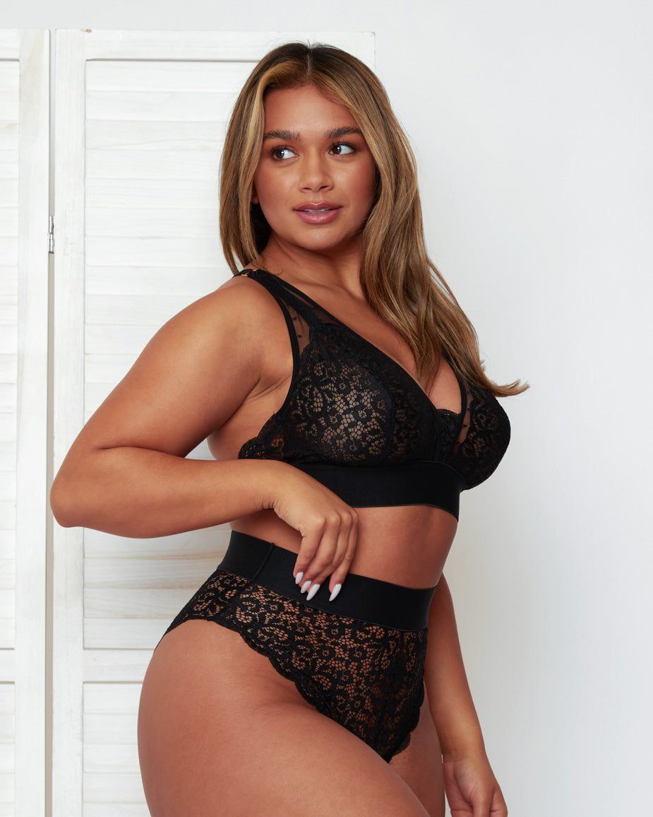 Model wearing the Hallie Bralette and High Waist Brief in Black by Tutti Rouge, featuring floral lace cups, sheer mesh panels, a plunging neckline, and a supportive wide underband.