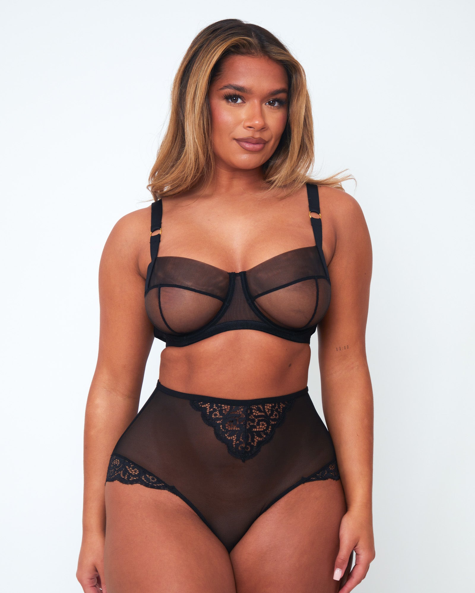 Front view of model wearing Tutti Rouge Raya black underwired balcony bra and high-waisted black mesh briefs with floral lace panels.