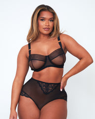 Model wearing Tutti Rouge Raya black sheer mesh balcony bra with gold strap rings, paired with high-waisted lace and mesh briefs.