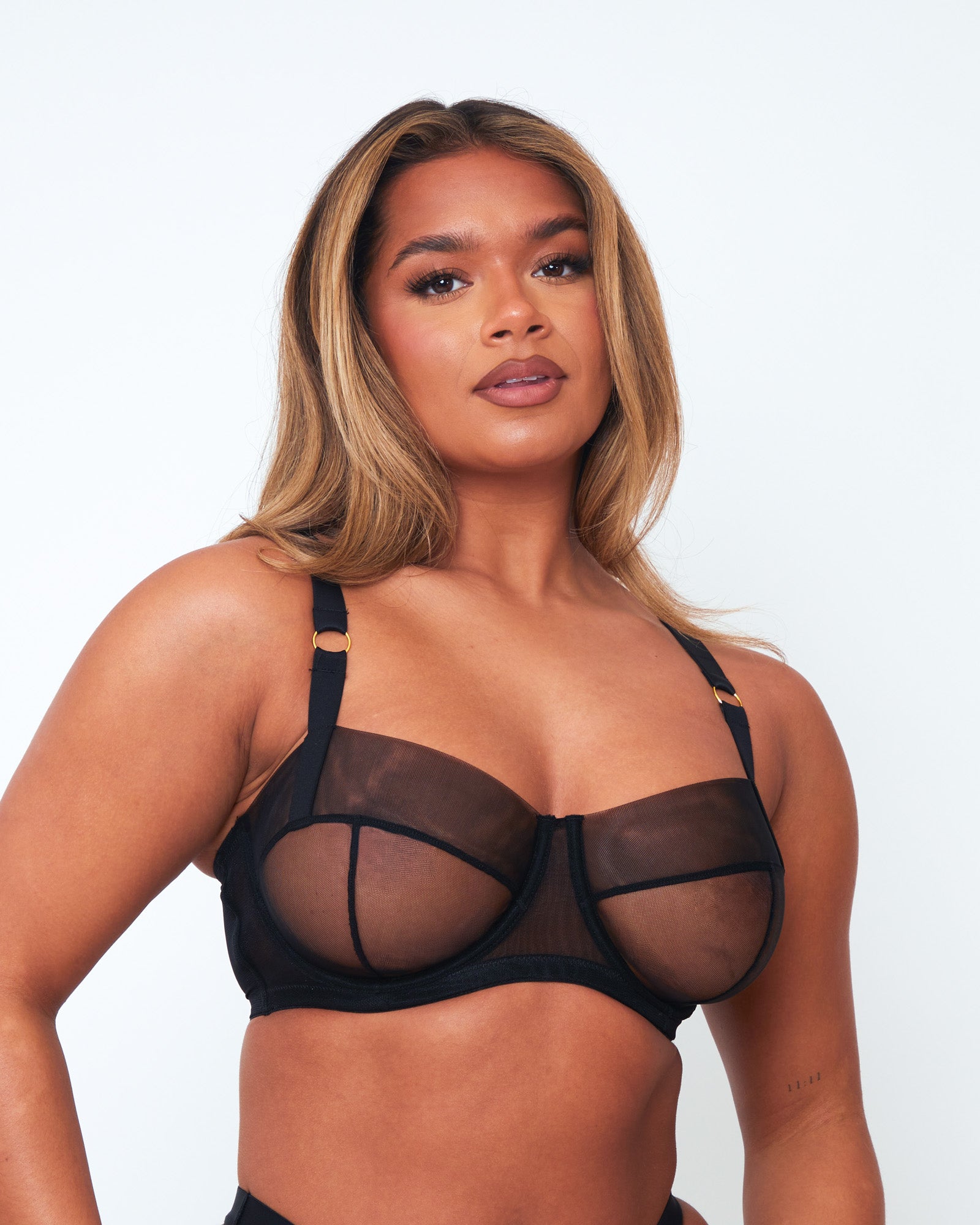 Close-up of Tutti Rouge Raya black balcony bra on a model, showing sheer mesh cups, black seam detailing and gold strap rings.