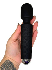 Black handheld massager held in a hand on a white background