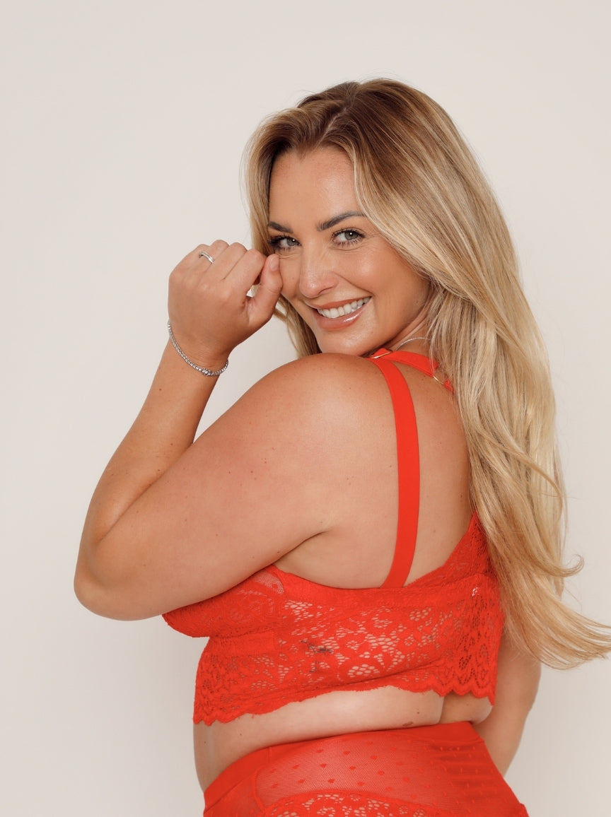 Woman wearing a red lace outfit against a plain background
