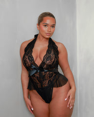 Front view of the Tutti Boudoir Imani Teddy in Onyx Black, featuring delicate floral lace, a plunging halter neckline, satin waist ribbon and playful mesh frill detailing designed to flatter your curves.