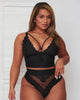 Model turning to show Tutti Rouge’s black lace bralette and matching high-waisted briefs, featuring a strappy plunge neckline, wide underband and sheer lace detailing.