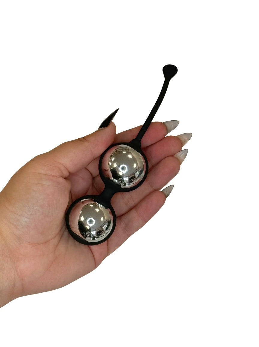 Metallic silver Kegel balls in hand for size context